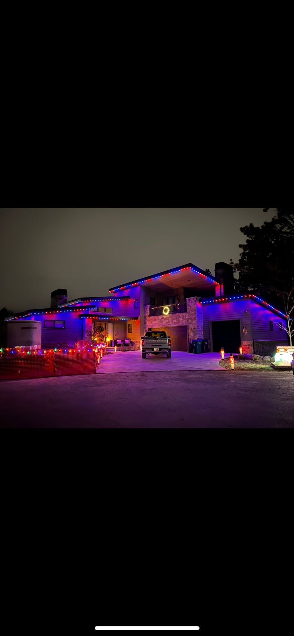 A home at night lit edge-to-edge in blue and red with permanent lighting.